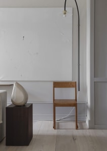A minimalist living room featuring a wooden chair and artwork.
