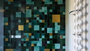 Modern bathroom featuring green and gold tiles on walls and floor.