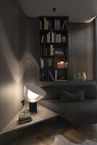 A modern living room featuring a sleek, minimalist concrete corner with a built-in bookshelf and contemporary lighting fixtur