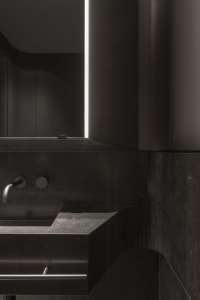 A modern bathroom with black marble surfaces and minimalist design.