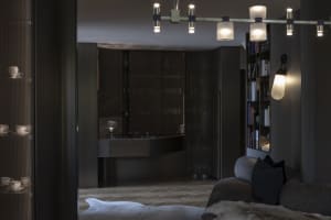 A modern dark-themed interior featuring a living room and bar area with dark wooden finishes and minimalistic design elements