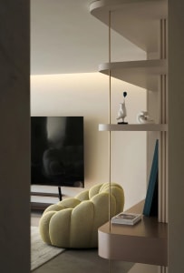 A modern minimalist living room featuring a yellow fabric armchair, a sleek television mounted on the wall, and a contemporar