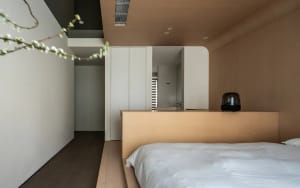 Minimalist bedroom with a wooden platform bed and upholstered bedding.