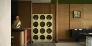A modern living room with wooden paneling, a display cabinet with circular cutouts containing decorative items, and a woman s