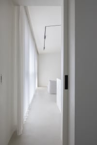 A minimalist interior space with white walls, glass walls, and a sleek, modern design.