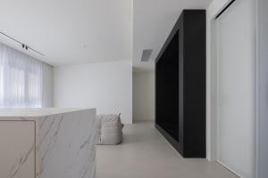 Modern minimalist living room with a white marble countertop and black walls.