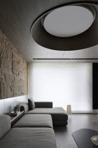 The image depicts an industrial-style living room with a modern concrete wall and a ceiling light fixture.