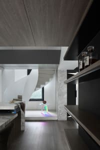 A modern minimalist kitchen featuring marble countertops, concrete floors, and wooden cabinets.
