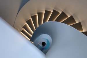 Modern staircase with wooden steps and railings, illuminated by soft, ambient lighting.
