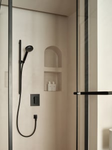 Modern bathroom shower featuring concrete and black metal materials.