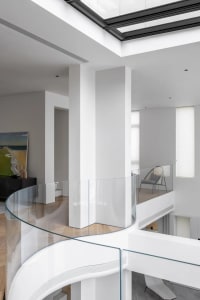 Modern residential interior design featuring glass railings and white walls.