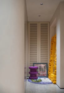 A vibrant hallway scene featuring colorful decor, a textured wall, and a purple stool.