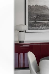 A modern living room featuring a sleek, minimalist design with a striking marble accent table and white accent chair.