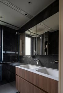 Modern minimalist bathroom featuring black tiles and white countertops.