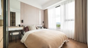 Modern bedroom with fabric bedding and wooden flooring.