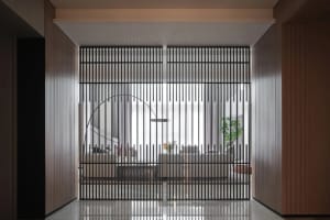 Modern interior design featuring a metal door with vertical bars and a curved handle.