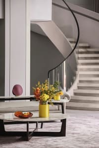 A modern living space featuring a circular marble coffee table, a comfortable sofa adorned with modern decor, and a stylish v