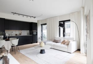 A modern living room with neutral-toned furniture, minimalist decor, and a white rug on a wooden floor.