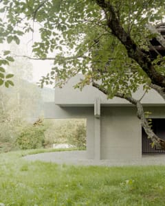A modern concrete building surrounded by greenery.