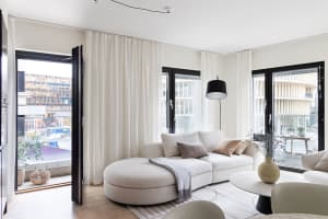 A modern living room with white furniture, fabric upholstery, and large windows.