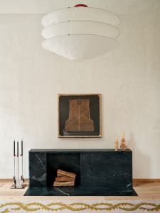 Modern living room decorated with a black marble fireplace and a pendant light with stacked white circular shades.