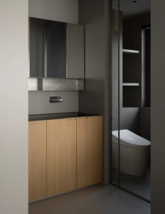 Modern bathroom with wooden vanity, glass wall, and metal fixtures.
