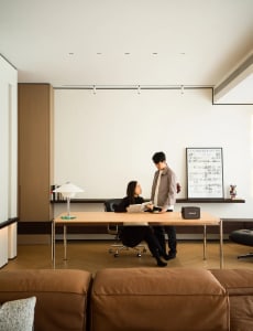 Modern minimalist office space featuring a sleek desk, comfortable seating, and a contemporary art piece on the wall.