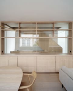 A minimalist living room with wooden furniture and shelves.