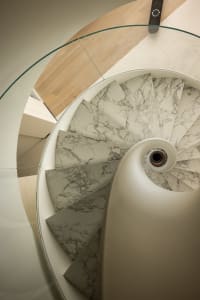 A modern minimalist spiral staircase with marble steps.