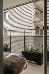 A modern, minimalist residential balcony featuring metal railings and planters.