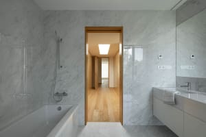 A minimalist bathroom with marble walls and a white bathtub.