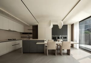 A modern kitchen with stone countertops, white cabinets, and stainless steel appliances.