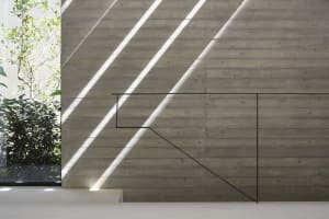 Modern concrete staircase with minimalist black railing and sunlight filtering through the window.