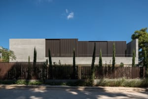 A modern two-story house with concrete walls and wooden accents.