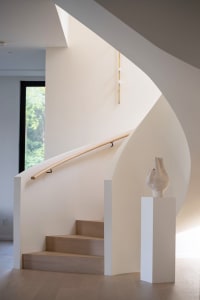 A modern staircase with white walls, wood steps, and a wooden handrail.