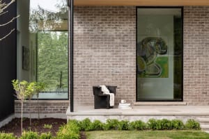 Modern minimalist residential interior featuring brick walls, concrete floors, and large glass windows.