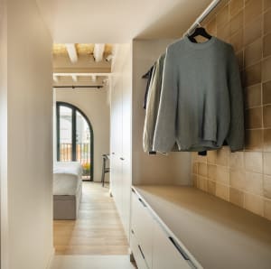 Clothes hanging on a tile wall cabinet in a minimalist closet.