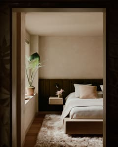 A cozy bedroom with a soft fur rug, beige walls, and a minimalistic bed frame.