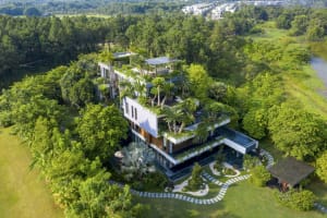 A modern house exterior surrounded by trees and greenery, featuring a metallic roof and outdoor seating areas.