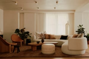Modern minimalist living room with mid-century wood and fabric elements, featuring a large sofa, coffee table, and decorative