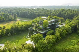 Modern residential house surrounded by green trees with green roof materials visible.