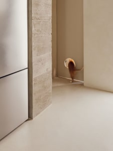 Minimalist living room with concrete walls and floor, featuring a round window.