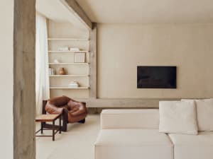 A minimalist living room with concrete shelving, a leather armchair, and a white sofa.