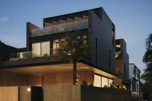 Modern concrete home exterior with glass windows and wooden accents.
