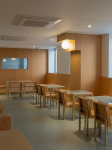 Modern restaurant interior featuring wooden seats and tables with a minimalist design.