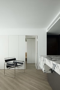 Minimalist living room with a marble countertop, white cabinets, a black chair, and a wood floor.