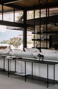 A modern living room with minimalist furniture, white cushions, and a sleek black console table.