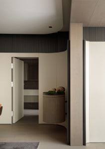 A modern minimalist apartment entrance with a wooden column and a round wooden bin.