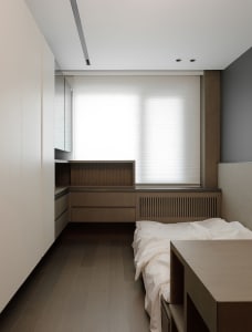 A modern minimalist bedroom featuring wooden cabinets and a bed.