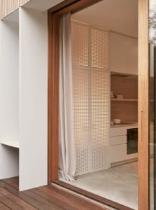A modern minimalist kitchen with concrete flooring and wooden cabinetry.